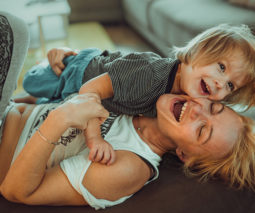 Mother lying on couch with toddler boy laughing - feature