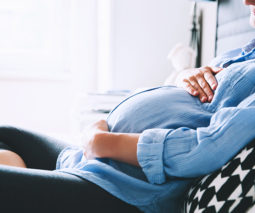 Pregnant woman sitting on couch relaxing with belly - feature