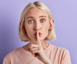 Blonde woman saying shhh with finger on lips - feature