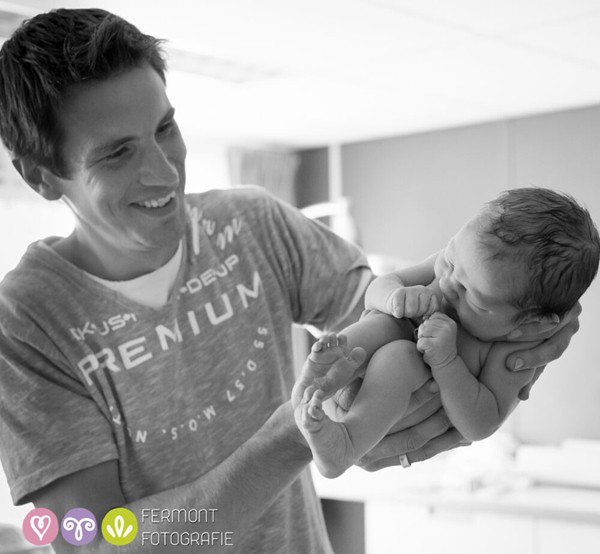 father holding curled up newborn baby in his hands