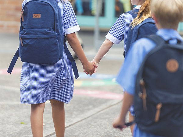 School girl holding hands with a friend in playground