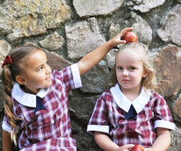 Two young school girls with an apple feature