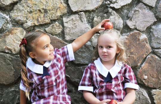 Two young school girls with an apple feature