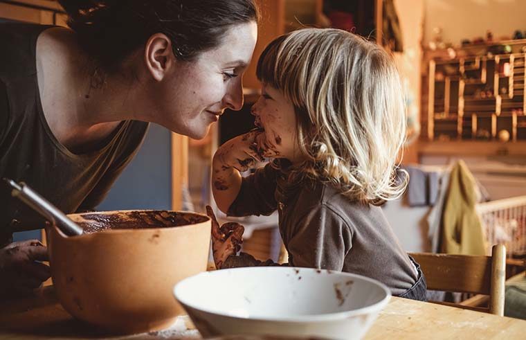 Mother and toddler cooking in kitchen with chocolate