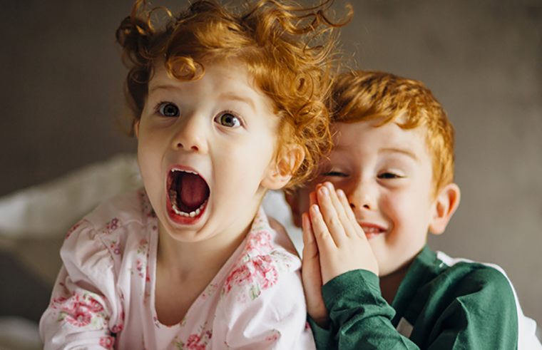 Redhead sister and brother laughing in pyjamas