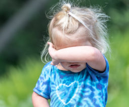 Toddler girl covering face with arm - feature