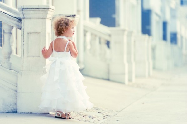 young girl in white sundress standing outside on sunny day