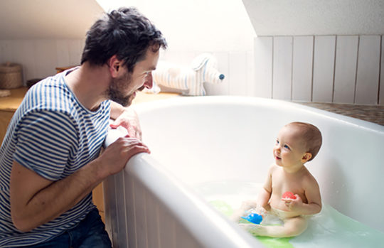 Father washing baby in the bath - feature