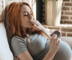 Pregnant woman reclining eating an iced donut