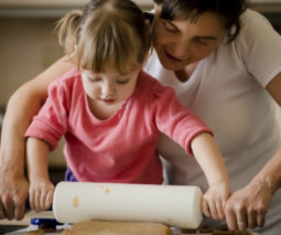 Mother helping child cook with rolling pin - feature