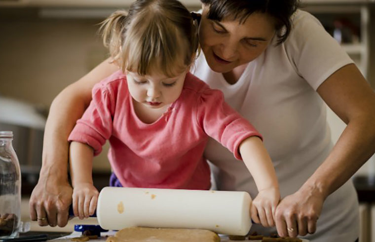 Mother helping child cook with rolling pin - feature