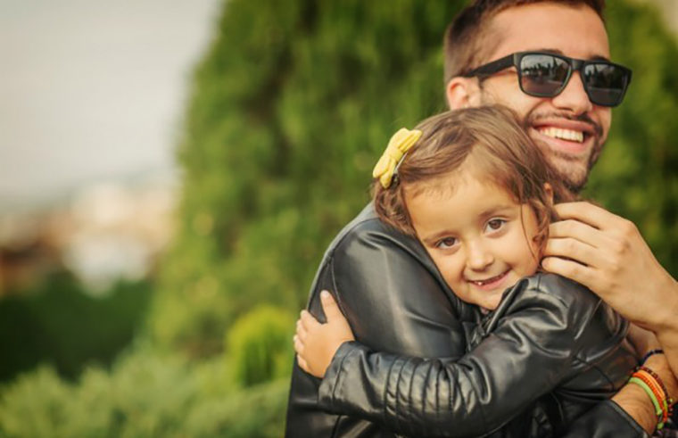 Father hugging young daughter wearing leather jacket - feature
