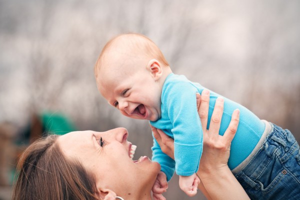 A mother lifting her adorable 3 month old baby boy as they laugh together.