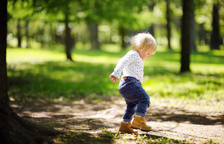 Toddler wearing boots climbing outdoors - feature