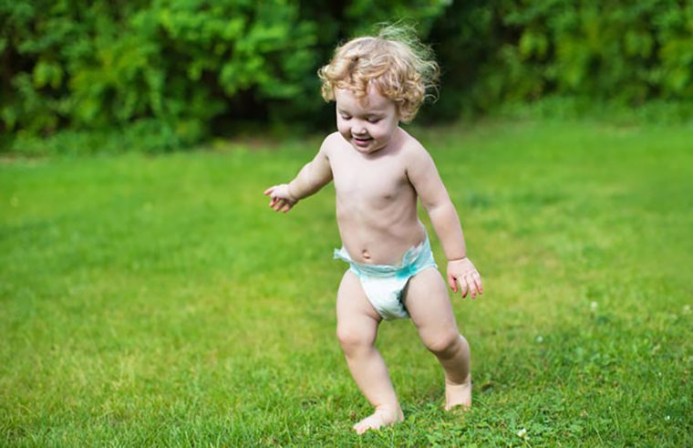 Toddler wearing nappy running in grass - feature
