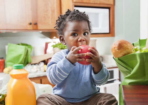 little boy eating apple in kitchen