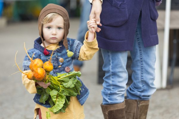 Adorable hipster child with beets at outdoor farmers market