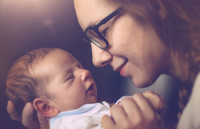 Mother wearing glasses holding newborn - feature