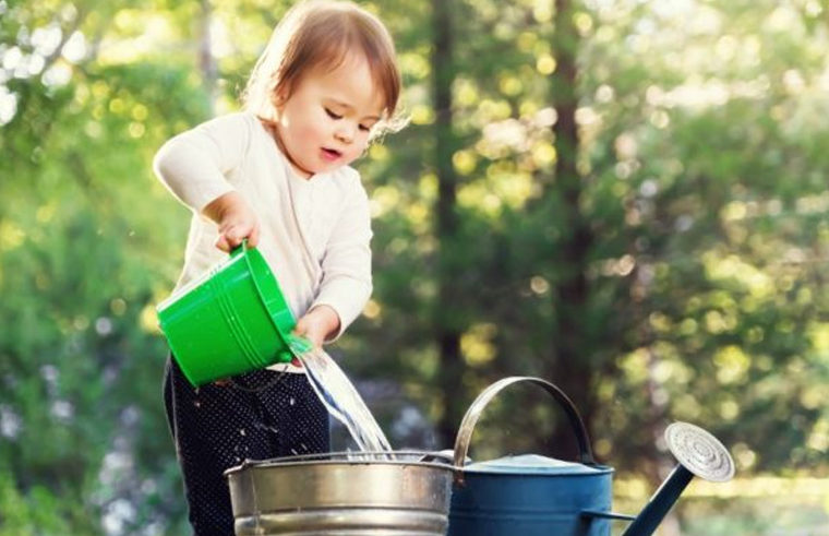 Toddler pouring water with buckets and watering can