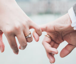 Couple holding hands with wedding rings - feature