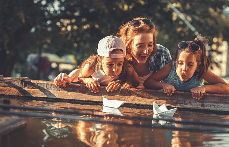 Mother and daughters testing paper boats on water