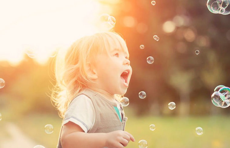 Toddler happily playing outdoors with bubbles