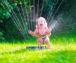 Toddler playing in sprinkler in backyard