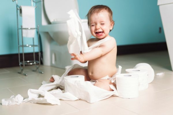 A Toddler ripping up with toilet paper in bathroom