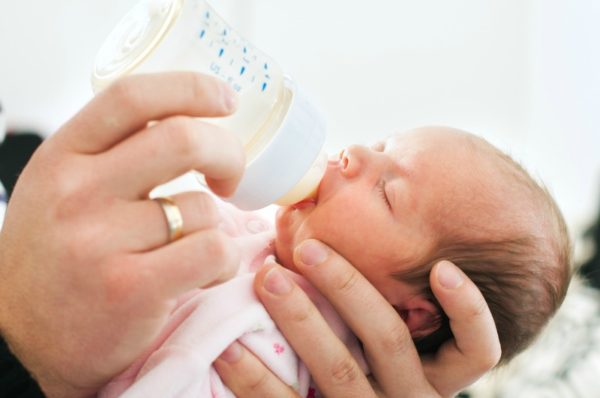 Newborn baby drinks from bottle