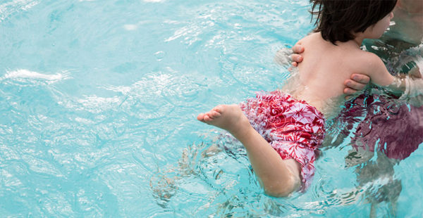 Child in pool swimming with parent