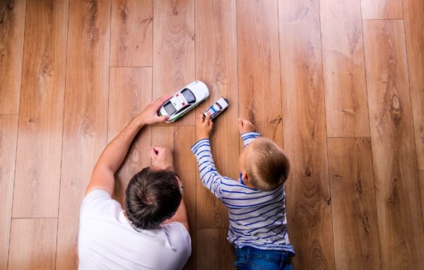 Dad playing cars on the floor with his son