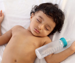 Sleeping toddler with bottle - feature