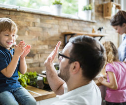 Dad giving son high five on kitchen bench - feature
