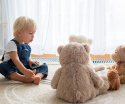 Baby boy in overalls talking to teddy bears - feature