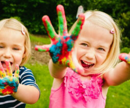 Two young girls with colourful paint on their hands - feature