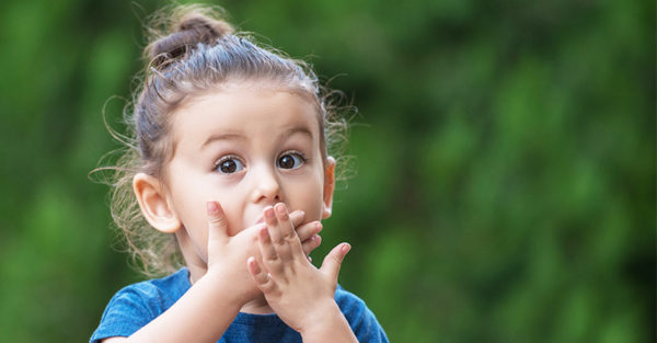 Little girl looking surprised with hands over mouth