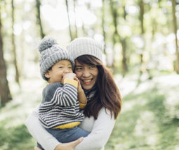 Asian mother and baby in woods wearing beanies - feature