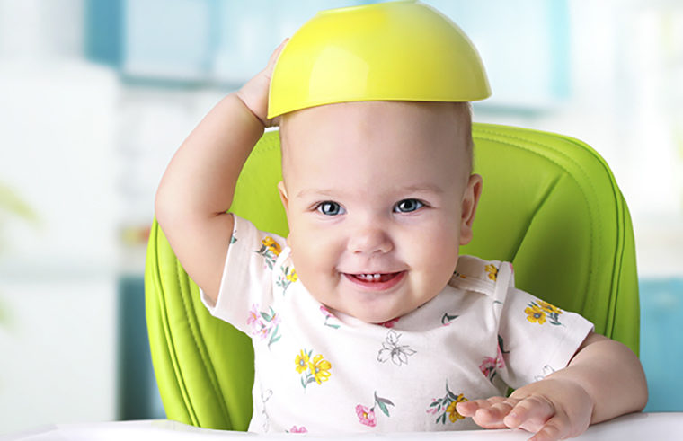 Baby sitting in highchair with bowl on head - feature
