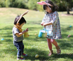Two Asian children on an Easter egg hunt in a park - feature