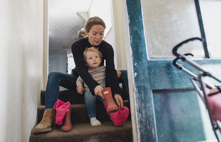 mother sitting on step putting on shoes for toddler
