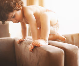 Toddler in nappy climbing on couch - feature