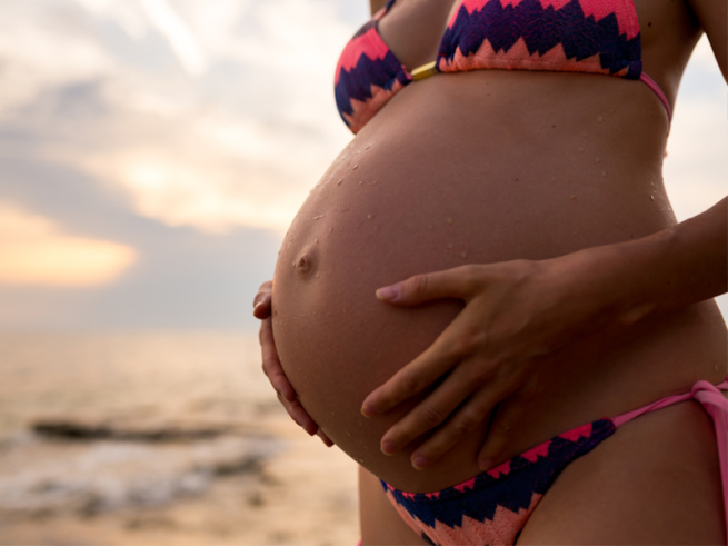 Pregnant woman at beach in bikini