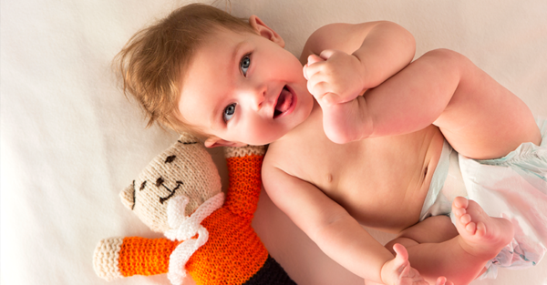 Smiling baby with knitted bear toy