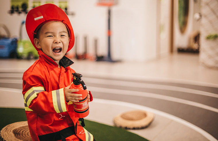 Young child in fireman dress up costume playing - feature