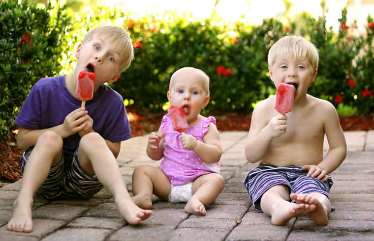 three siblings baby eating ice blocks