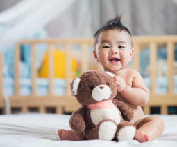 Asian baby sitting smiling with teddy - feature