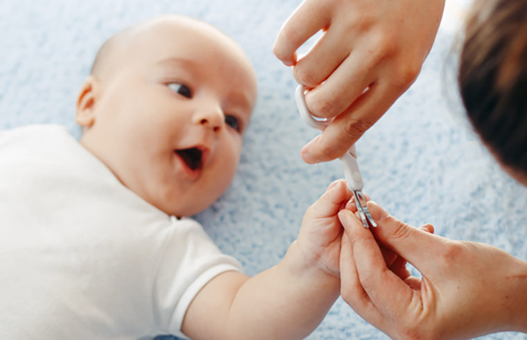 Baby getting nails clipped with scissors - feature