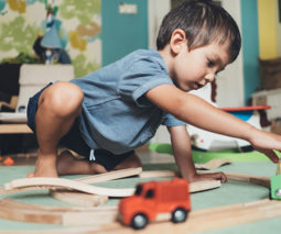 Boy playing with toy train and tracks -feature