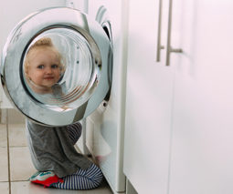 Child putting clothes in washing machine