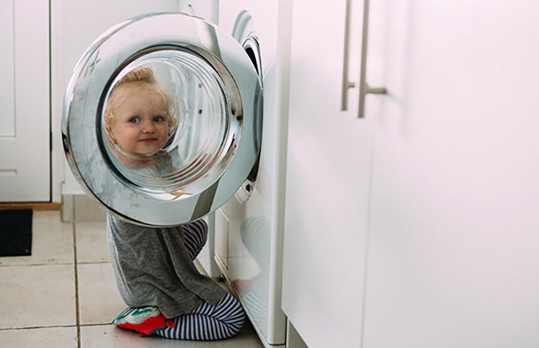 Child putting clothes in washing machine